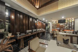 a restaurant with wooden walls and tables and chairs at Gaing Mas Jimbaran Villas by Gaing Mas Group in Jimbaran