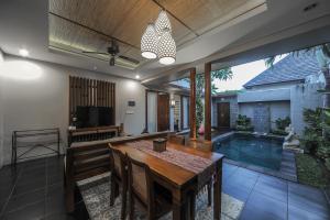 a dining room with a table and a swimming pool at Gaing Mas Jimbaran Villas by Gaing Mas Group in Jimbaran