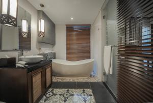 a bathroom with a large tub and a sink at Gaing Mas Jimbaran Villas by Gaing Mas Group in Jimbaran