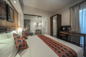 a hotel room with a large white bed and a television at Gaing Mas Jimbaran Villas by Gaing Mas Group in Jimbaran