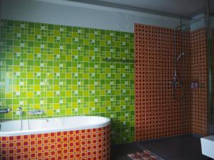 a bathroom with a tub and green and orange tiles at Maderla in Bangkok +93 photos