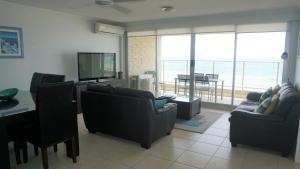 Sala de estar con sofás, TV y mesa en Pacific Surf Absolute Beachfront Apartments, en Gold Coast