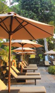 una fila de sillas y sombrillas en un patio en Besakih Beach Hotel, en Sanur
