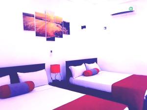 a bedroom with two beds and a painting on the wall at My Home Guest in Polonnaruwa