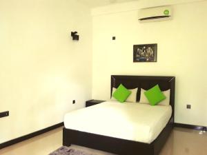 sypialnia z łóżkiem z zielonymi poduszkami w obiekcie My Home Guest w mieście Polonnaruwa