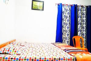a bedroom with a bed with blue curtains at vinyaka p.g.house in Rāmnagar