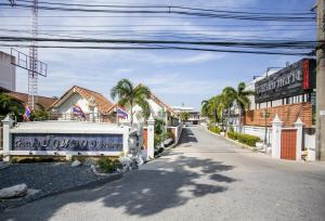 a street with a white fence and palm trees at Bualuang HOTEL in Ang Thong