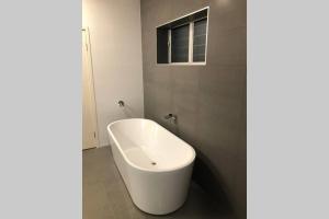 a white bath tub in a bathroom with a window at Malibu Apartment - Peregian Beach in Peregian Beach