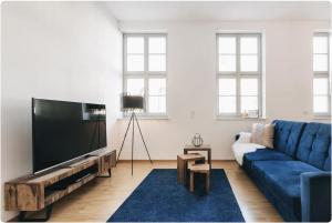 ein Wohnzimmer mit einem blauen Sofa und einem Flachbild-TV in der Unterkunft Apartment direkt an der Frauenkirche, Jüdenhof, FEWO-Residenz-Dresden in Dresden