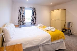 a bedroom with a large white bed and a window at Elm – Three Tuns Apartments in Pettistree
