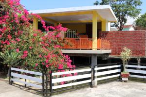 a house with a white fence and pink flowers at OYO 1722 Villa Ciparay Indah Syariah in Garut