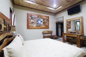 ein Schlafzimmer mit einem Bett, einem Schreibtisch und einem Spiegel in der Unterkunft Alloyna Country Cottage Brastagi in Berastagi