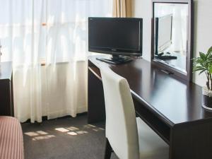 東京的住宿－HOTEL LiVEMAX BUDGET Higashi Ueno，一张桌子,电视机和椅子放在房间里