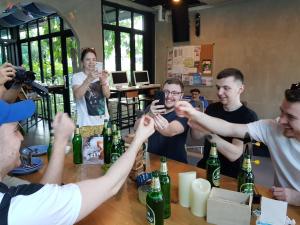 een groep mensen die rond een tafel zitten met bierflessen bij Wayha Hostel Don Mueang Airport in Bangkok