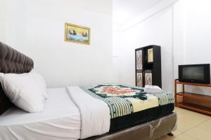 a bedroom with a bed and a tv at Villa Keluarga Bre Batunanggar in Berastagi