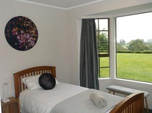 een slaapkamer met een bed en een groot raam bij Waitomo Golf Ridge in Waitomo Caves