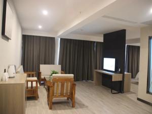 済寧市にあるThank Inn Plus Hotel Shandong Qufu Kongfuのリビングルーム(テレビ、テーブル、椅子付)