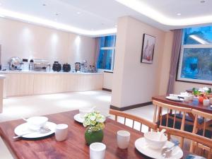 cocina y comedor con mesa de madera y sillas en Thank Inn Plus Hotel Hubei Ezhou Echeng District Wuhan East Ocean World, en Ezhou