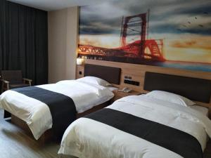 two beds in a hotel room with a painting on the wall at Thank Inn Plus Hotel Anhui Chizhou Jiuhuashan Scenic Area Yonghua Road in Chizhou