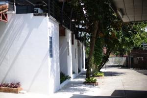 a white building with a tree next to a sidewalk at First Residence in Mae Rim