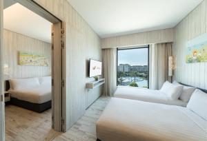 a hotel room with two beds and a window at Village Hotel Sentosa by Far East Hospitality in Singapore