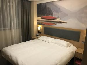 a bed in a hotel room with a painting on the wall at Thank Inn Plus Hotel Jiangsu Taizhou Gaogang Port Middle School in Taizhou