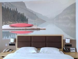 een slaapkamer met een schilderij van een meer en een bed bij Thank Inn Plus Hotel Jiangxi Fuzhou Jinxi County Government Square in Fuzhou