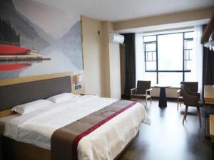BaishuiにあるThank Inn Plus Hotel Hunan Yongzhou Jiangyong County Yonghua Internationalの大きなベッドとデスクが備わるホテルルームです。