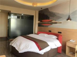 - une chambre avec un grand lit orné d'une peinture murale dans l'établissement Thank Inn Plus Hotel Hebei Shijiazhuang Wuji County Bus Station, à Shijiazhuang