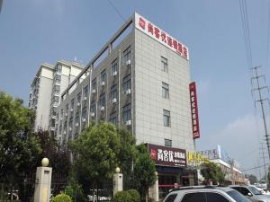 a white building with a sign on top of it at Thank Inn Plus Hotel Shandong Zaozhuang Tengzhou Parallel Road Qinghe Shangcheng Community in Zaozhuang