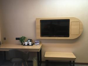 a room with a desk with a tv on the wall at Thank Inn Plus Hotel Hubei Jingzhou City Jingzhou District Railway Station in Jingzhou