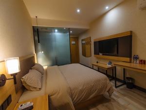 a hotel room with a bed and a television at Up And In Anhui Wuhu Anhui University of Engineering in Wuhu