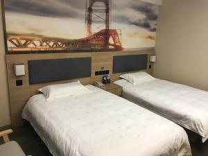 two beds in a hotel room with a painting on the wall at Thank Inn Plus Hotel Jiangsu Taizhou Gaogang Port Middle School in Taizhou