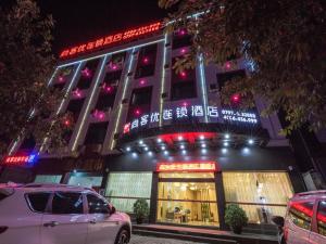 a building with neon signs and cars parked in front of it at Thank Inn Plus Hotel Jiangxi Ganzhou Nankang District East Bus station in Ganzhou