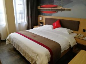 een hotelkamer met een groot bed met rode kussens bij Thank Inn Plus Hotel Guangdong Zhaoqing Gaoyao City Yaonan 2nd Road in Zhaoqing