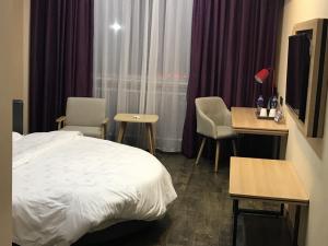 a hotel room with a bed and a table and chairs at Thank Inn Plus Hotel Jiangsu Taizhou Gaogang Port Middle School in Taizhou