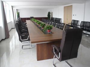 een conferentieruimte met een lange houten tafel en zwarte stoelen bij Thank Inn Plus Hotel Shandong Qufu Kongfu in Jining