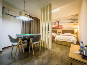 a hotel room with a bedroom with a table and a bed at Thank Inn Plus Hotel Jiangxi Ganzhou Nankang District East Bus station in Ganzhou