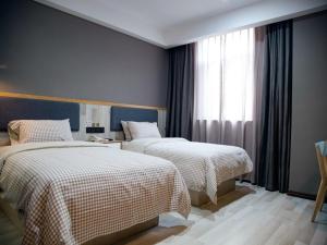 a hotel room with two beds and a window at Up And In Anhui Chizhou Guichi DistrictAnhui University of Engineering in Chizhou