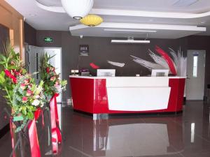 un mostrador rojo y blanco en un vestíbulo con flores en Thank Inn Plus Hotel Shandong Weihai Rongcheng City Chengshan Avenue Rt-mart en Weihai