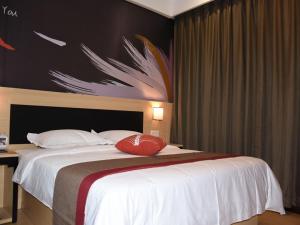1 dormitorio con 1 cama blanca grande y una pintura en la pared en Thank Inn Plus Hotel Chongqing Wanzhou District Pedestrian Street, en Wanxian