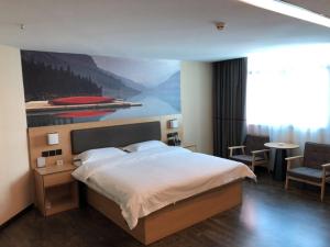 a bedroom with a bed and a painting on the wall at Thank Inn Plus Hotel Yunnan Honghe Gejiu City Renmin Road in Gejiu