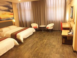 Cette chambre d'hôtel comprend deux lits, une table et des chaises. dans l'établissement Thank Inn Plus Hotel Jiangsu Huaian Qingpu District Evergrande, à Huai'an
