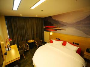 a hotel room with a large bed and a table at Thank Inn Plus Hotel Yunnan Honghe Gejiu City Renmin Road in Gejiu