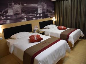 a hotel room with two beds with red pillows at Thank Inn Plus Hotel Chongqing Wanzhou District Pedestrian Street in Wanxian