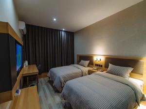 a hotel room with two beds and a flat screen tv at Up And In Anhui Wuhu Anhui University of Engineering in Wuhu
