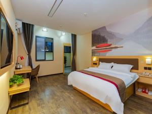 成都市にあるThank Inn Plus Hotel Sichuan Chengdu Jianyang Dongcheng Huafuの大きなベッドとデスクが備わるホテルルームです。