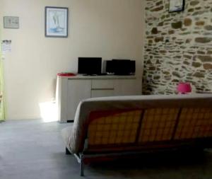 a living room with a bed and a stone wall at Studio avec jardin clos et wifi a Hirel in Hirel