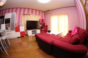 uma sala de estar com um sofá vermelho e uma televisão em Pop Culture House em Takayama