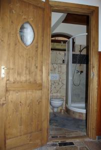 a bathroom with a wooden door and a toilet at Dabasi Lovas Vendégház in Dabas